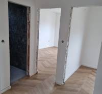Chodba ve 4pokojovém bytě s dřevěnou podlahou a otevřenými dveřmi.