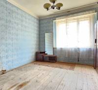 Pokoj s dřevěnou podlahou, modrou tapetou a vintage nábytkem na Pozemky - bydlení.