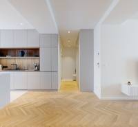 Prostorný kuchyňský kout a obývací pokoj v 3-pokojovém bytě s dřevěnou podlahou a moderním vybavením.