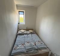 Malá ložnice s úzkým oknem a postelí v 3-pokojovém bytě.