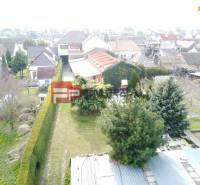 Rodinný dům v Trnavě se zahradou, stromy a okolím plným dalších domů.