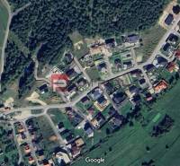 Letecký pohled na pozemky - bydlení v Pružině obklopené zelenými plochami a lesem.