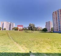 Zeleň a věžáky na Koprivnické 9/F, Bratislava IV, s otevřeným prostorem pro odpočinek.