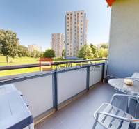 Balkon 1-pokojového bytu na Koprivnické 9/F v Bratislavě IV s výhledem na zeleň a paneláky.