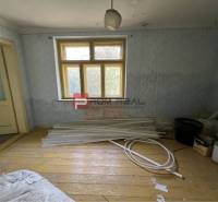 Místnost s dřevěnou podlahou, staré dveře, stavební materiál, slouží k rekonstrukci. Pozemky - bydlení.