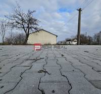 Povrch na ulici Partizánska, vedle sklady a haly, s holými stromy.