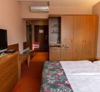 Pokoj v hotelu a penziony s televizí, skříní a manželskou postelí.