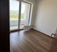 Pokoj s dřevěnou podlahou a balkonem ve 2pokojovém bytě.