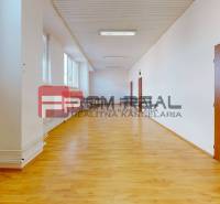 Prostorná chodba s dřevěnou podlahou a dveřmi ve skladových a halových prostorách.