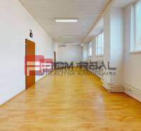 Prostorná světlá místnost s dřevěnou podlahou, radiátory a okny ve skladech a halách.