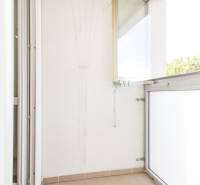 Zasklený balkon ve 3-pokojovém bytě s dlažbou a sušákem na prádlo.