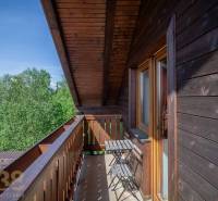Balkon se stolem a židlemi v Rekreačním apartmánu s výhledem na stromy ve Vysokých Tatrách.