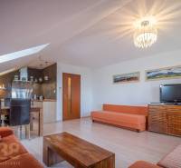 Obývací pokoj rekreačního apartmánu s pohovkami, jídelním stolem a televizí.