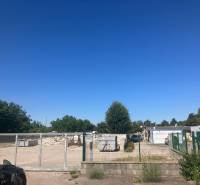 Pozemky - komerční na Popradské ulici v Bratislavě - Podunajské Biskupice s bránou a kontejnery.