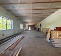 Interiér skladů a hal s dřevěnou podlahou, regály a stavebním materiálem.