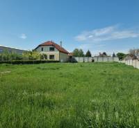 Pozemky - bydlení v Cabaji-Čápore s travnatou plochou a domem v pozadí.