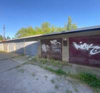 Garáže ve Zvolenu s graffiti na vratech, obklopené zelení a betonovou plochou.