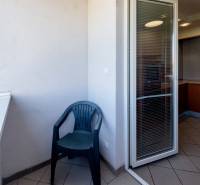 Balkon s plastovou židlí a přístupem do kuchyně ve 3pokojovém bytě.