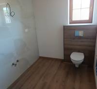Koupelna v chatě s toaletou, dřevěnou podlahou a nástěnným vytápěním.