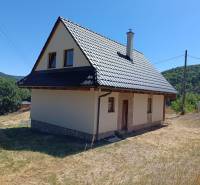 Chata v Horních Hamrech s plechovou střechou a okolní přírodou, pod modrou oblohou.