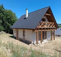 Chata v Horních Hamrech s dřevěným balkónem, obklopená přírodou a svěží zelení.