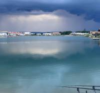 Jezero obklopené domy v Boldogu, pozemky - bydlení, dramatická obloha před bouří.