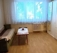 Pokoj v 3-pokojovém bytě s pohovkou, stolkem a velkou skříní.