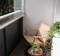 Balkon 2-pokojového bytu s křeslem, stolkem a rostlinami.