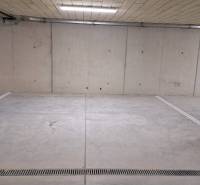 Parkovací místo v podzemní garáži s betonovými stěnami a podlahou.