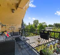 Balkon rodinného domu s pohodlným posezením, výhledem na zahradu a zeleň.