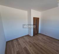 Pokoj s dřevěnou podlahou a bílými stěnami, součást 2-pokojového bytu.