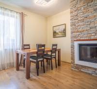 Jídelna v rekreačním apartmánu s dřevěným stolem a krbem obloženým kamenem.