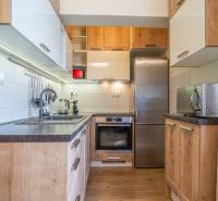 Kuchyně v rekreačním apartmánu s dřevěnou podlahou a moderním vybavením.