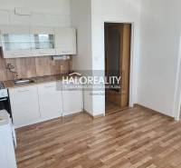 Kuchyňská linka v 1-pokojovém bytě s dřevěnou podlahou a bílými skříňkami.