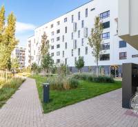 Exteriér bytového domu s chodníkem, zelení a dětským hřištěm na Seberíniho ulici, Bratislava - Ružinov.