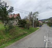 Cesta u rodinného domu v obci Velká Lesná, obklopená zelení a stromy.
