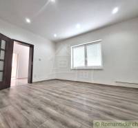 Rodinný dům s laminátovou podlahou, bílými stěnami a oknem s vnitřními žaluziemi.
