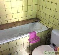 Koupelna v rodinném domě s vanou a toaletou, obklopená žlutými kachličkami.