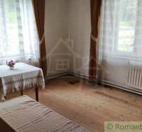 Interiér rodinného domu s dřevěnou podlahou, stolem a dlouhými záclonami.