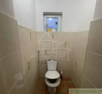 Malá koupelna s keramickými obklady, WC a oknem v rodinném domě.