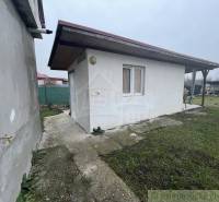 Zahradní altán u rodinného domu na zpevněné ploše s trávníkem a oplocením.