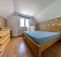 Ložnice s dřevěným nábytkem v rodinném domě, květinová tapeta, dřevěná podlaha.