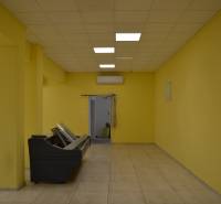Žluté stěny, dlažba a stropní světla v obchodních prostorách.