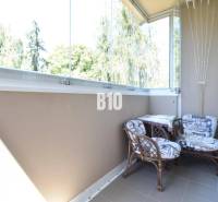 Zasklený balkon se dvěma židlemi ve 3pokojovém bytě s pěkným výhledem.