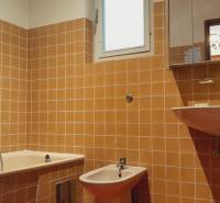 Koupelna s oranžovými kachličkami v rodinném domě, obsahuje vanu, bidet a umyvadlo.