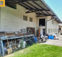 Exteriér gastro prostor v Grossinzersdorfu s uskladněnými materiály a motorkou na dvoře.