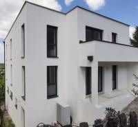 Vila v Hainburgu an der Donau s bílou fasádou, obklopená zelení a modrou oblohou.