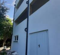 Vila v Hainburgu an der Donau s bílou fasádou a šikmým trávníkem při vstupu.