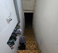 Schodiště vede do podzemí v rodinném domě, na schodech jsou položeny věci.