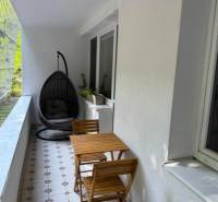 Zasklený balkon 4pokojového bytu s posezením a závěsným křeslem.
